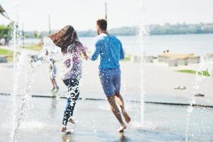 Group of friends having fun next to the public fountain on summer day photo