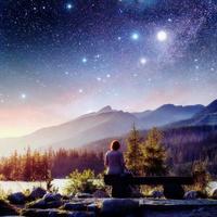 Lake Strbske pleso in High Tatras mountain, Slovakia, Europe. Fantastic starry sky and the milky way. The girl sits on a bench and looks into the fairy-tale sky. photo