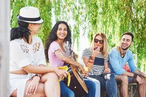 Group of happy friends with guitar. While one of them is playing guitar and others are giving him a round of applause photo