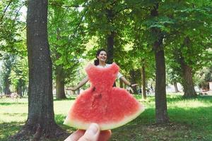 Creative concept photo of a watermelon as a dress with beautiful woman in park