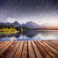 fantástico cielo estrellado y la vía láctea sobre un lago en el parque high tatras. shtrbske pleso, eslovaquia, europa foto