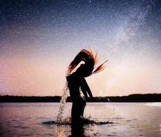 mujer en el fondo del agua en el cielo nocturno. fantástico cielo estrellado y la vía láctea foto