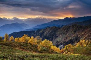 Autumn landscape and snowy mountain peaks. Birch forest in sunlight. Main Caucasian Ridge. Mountain View from Mount Ushba Mheyer, Georgia. Europe. photo