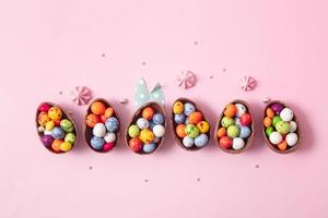 huevos de pascua de chocolate y decoración plana para niños concepto de huevo de caza de pascua sobre fondo rosa. dulces en forma de huevo foto