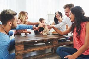 Group of creative friends sitting at wooden table. People having fun while playing board game photo