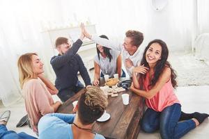 grupo de amigos creativos sentados en la mesa de madera. gente divirtiéndose mientras juega al juego de mesa. foto