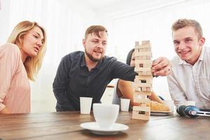 grupo de amigos creativos sentados en la mesa de madera. gente divirtiéndose mientras juega al juego de mesa. foto