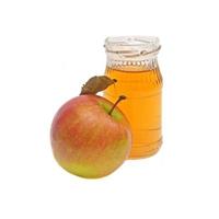 una manzana entera con hoja y una pequeña botella de vinagre de sidra de manzana aislada en fondo blanco. bebidas de categoría. foto