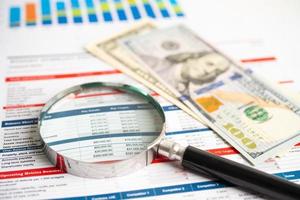 Magnifying glass on charts graphs spreadsheet paper with US dollar banknotes. Financial development, Banking Account, Statistics, Investment Analytic research data economy. photo
