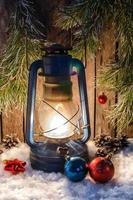 Kerosene lamp on the white snow lights Christmas decorations and fir branches on the background photo