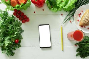 Phone for keeping a diary of weight loss on the background of vegetables. Drawing up an individual diet. photo