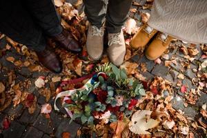 pies de la novia y el novio, así como de su hijo en el fondo de las hojas de otoño