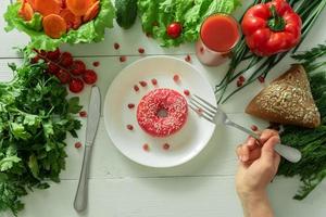 un delicioso donut yace en un plato y come para comerlo. problemas de nutrición adecuada y el concepto de elegir entre alimentos sanos y no sanos foto