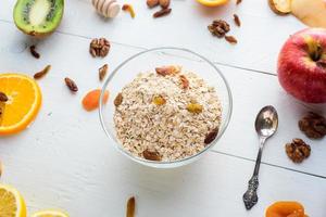 A plate with muesli surrounded by apples, kiwi, dried fruits, oranges and apples. Healthy eating concept. photo