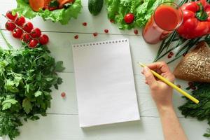 cuaderno para llevar un diario de pérdida de peso sobre el fondo de las verduras. elaboración de una dieta individual. foto