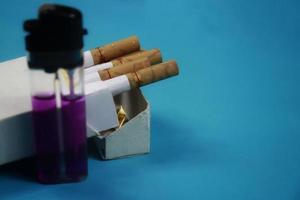 lighter and cigarette almost out of the pack on a blue background photo