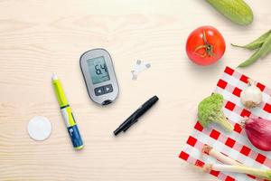 Blood glucose meter and insulin injection on the table beside to healthy food - vegetables. Top view, flat lay composition photo