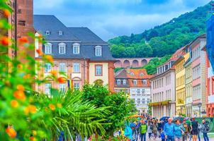 people tourists walking down pedestrian street with typical german houses with colorful walls in Heidelberg Old town historical centre photo