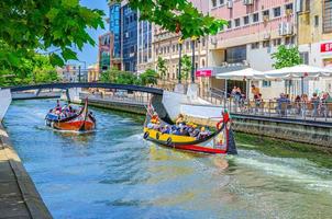 el paisaje urbano de aveiro con un tradicional y colorido barco moliceiro con turistas navegando en un estrecho canal de agua foto