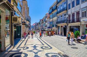 people tourists walking down Rua de Santa Catarina cobblestone pedestrian street with colorful buildings and houses in Porto