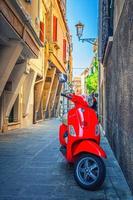 Chioggia, Italy, September 16, 2019 Red scooter motorbike Vespa in narrow italian street in historical town centre photo