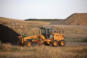 Grader by asphalt pile in scenic Saskatchewan photo