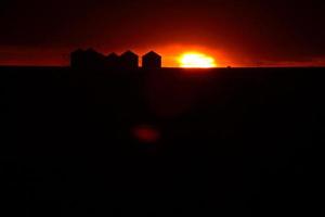 Sun setting behind metal granaries in Saskatchewan photo