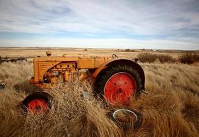 plantas rodadoras apiladas contra tractor abandonado foto