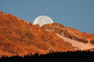luna llena detrás de la montaña en la pintoresca alberta foto