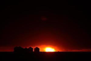 Sun setting behind metal granaries in Saskatchewan photo