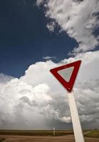 Yeild sign with Cumuloninumbus clouds in background photo