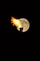 Full moon behind natural gas flame photo