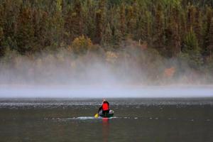 hombre en canoa cerca de la niebla de la mañana en el lago foto
