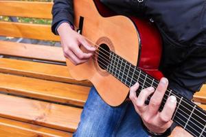 hombre en banco tocando guitarra acustica foto