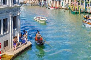 Gondolier and tourists on gondola traditional boat sailing on water of Grand Canal in Venice photo