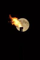 luna llena detrás de la llama del gas natural foto
