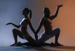 Beautiful sporty woman and man in white clothes doing yoga asanas together indoor photo