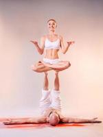 Beautiful sporty woman and man in white clothes doing yoga asanas together indoor photo