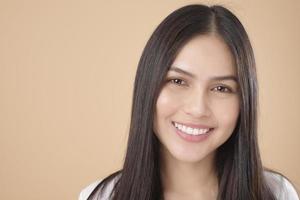 A Portrait of Asian woman with white T-shirt over Light brown background studio photo