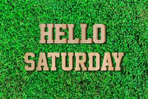 Hello saturday made from wooden alphabet on green leaf background. photo