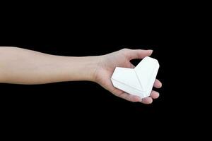 Hands holding origami heart isolated on black background. photo