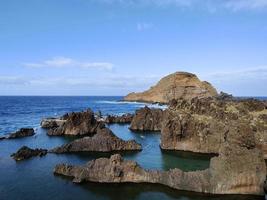 piscinas naturales en medio del océano atlántico en porto moniz, isla de madeira, portugal. tiempos de vacaciones increíbles. nubes con sol. océano y olas golpeando las rocas. gente en el agua. foto