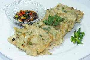 A traditional Javanese, Indonesian food made of tempeh coated with flour and half-fried green onions is called Tempe Mendoan photo