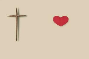 Wooden christian cross and red paper heart on light brown background for show love of god. free copy space