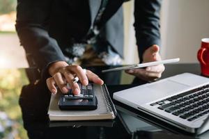 businessman working on desk office with using a calculator to calculate the numbers, finance accounting concept photo