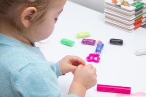 The girl at the table is playing with modeling dough. Childrens games for fine motor skills photo