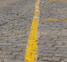 Texture of dark grey cobblestones with yellow stripe as road marking photo
