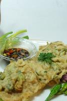A traditional Javanese, Indonesian food made of tempeh coated with flour and half-fried green onions is called Tempe Mendoan photo