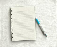 Notebook,pen on a white cloth background. top view copy space photo