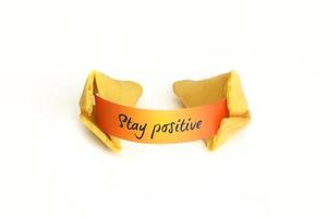 Closeup of a fortune cookie with Stay Positive wish on orange paper. photo